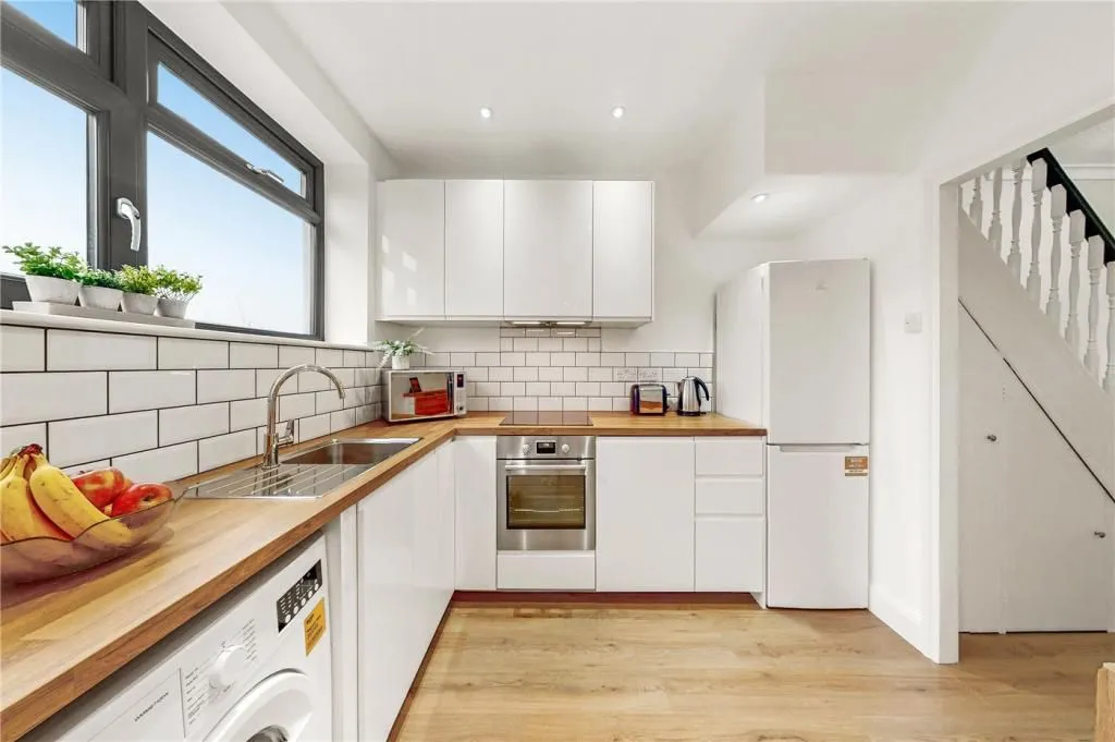 A kitchen with white cabinets and wooden counter tops.